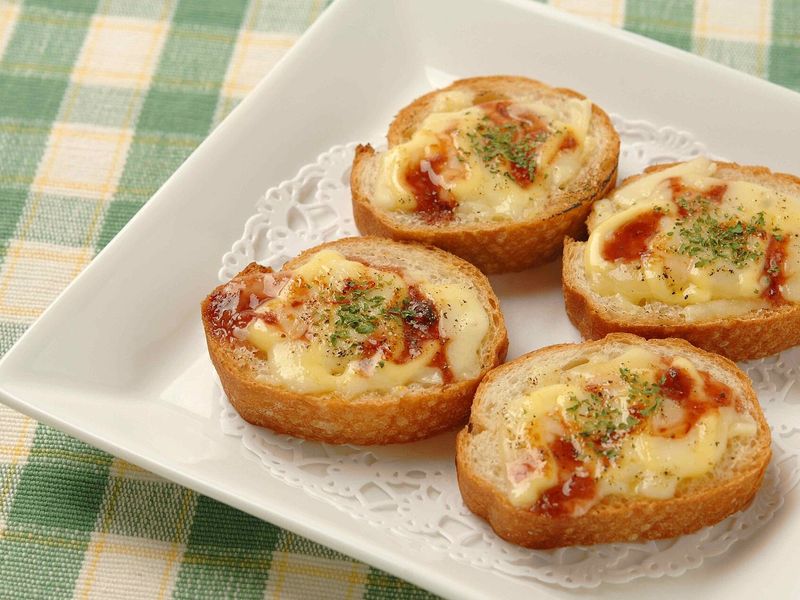 Горячие бутерброды из багета с расплавленным сыром, кетчупом и зеленью