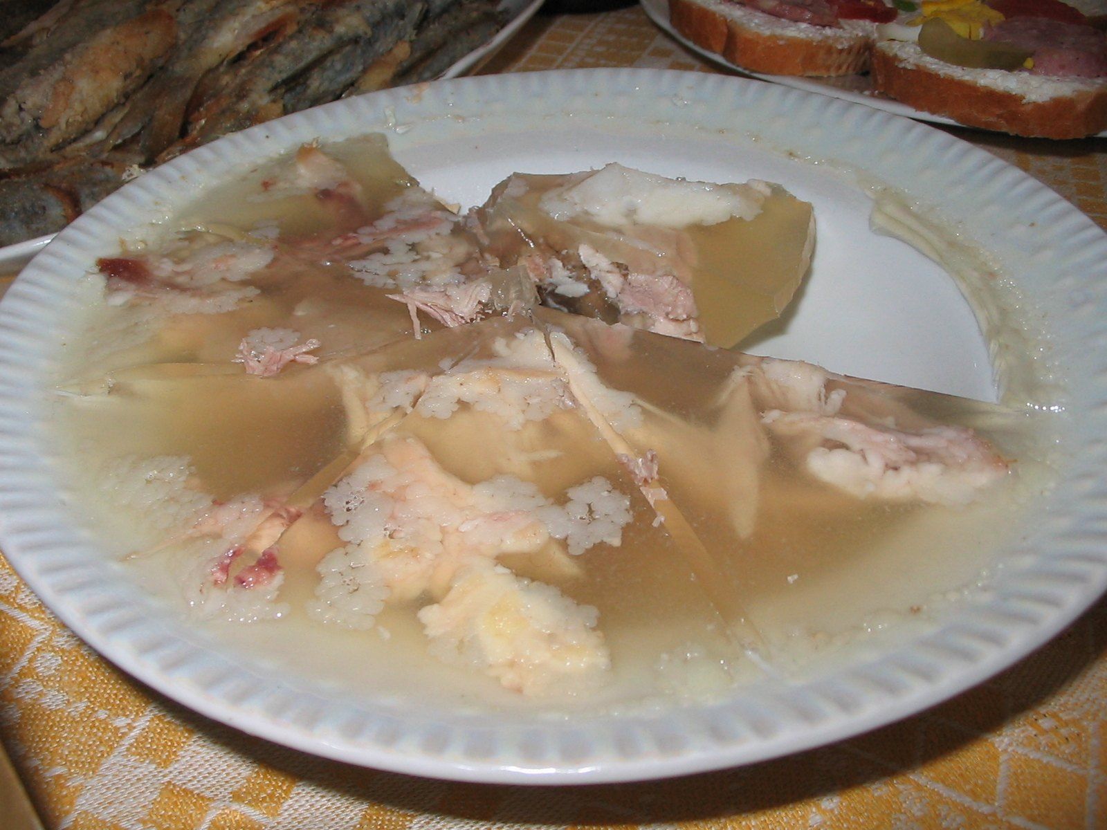 Холодец с кусочками мяса, застывший в тарелке и нарезанный на порции