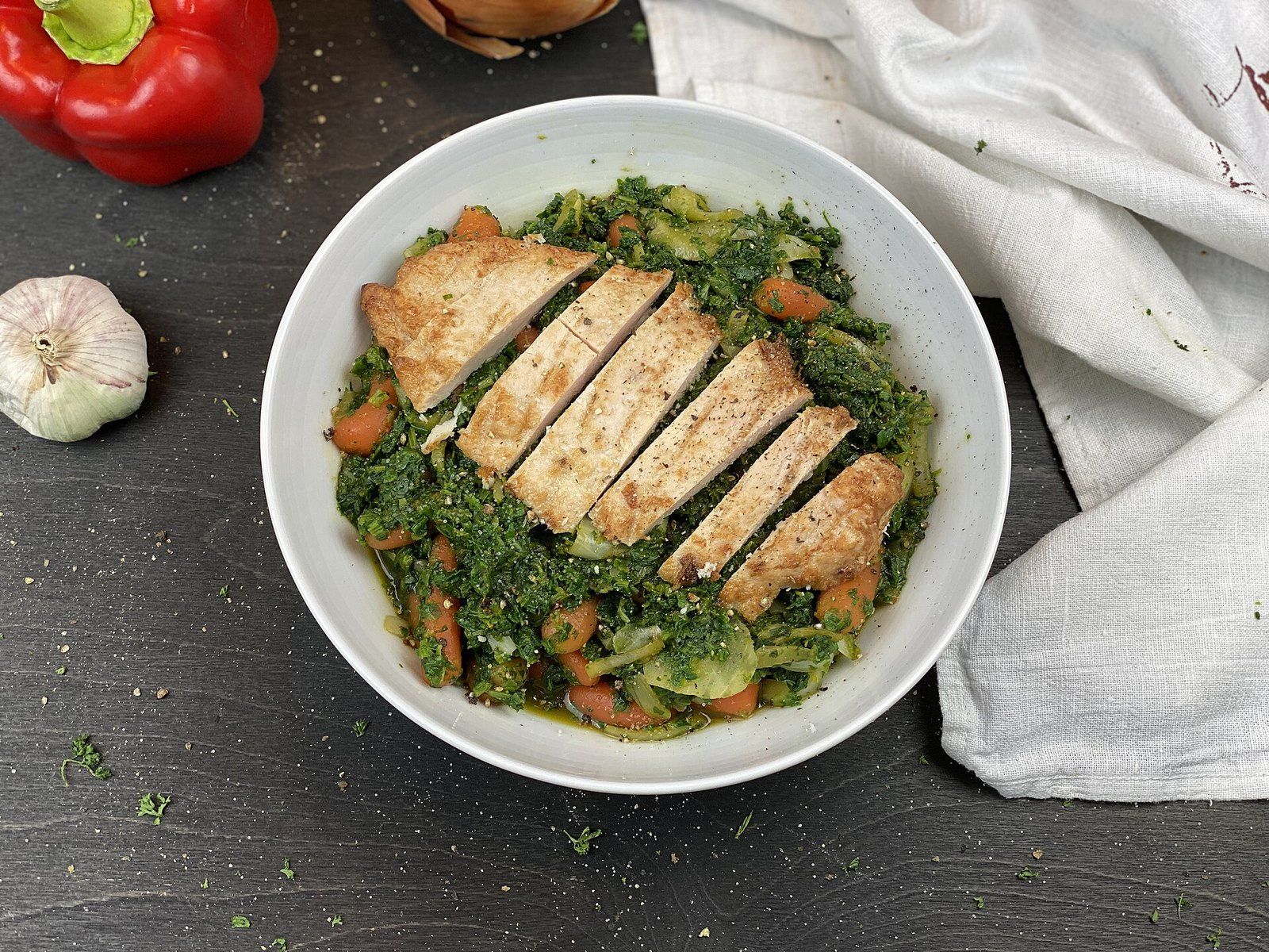 Нарезанная куриная грудка на тушёном шпинате с морковью