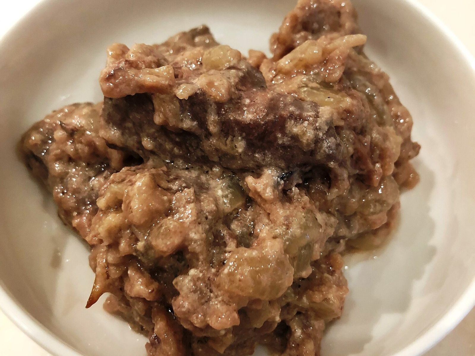 Кусочки печени с луком в сметанном соусе в белой миске