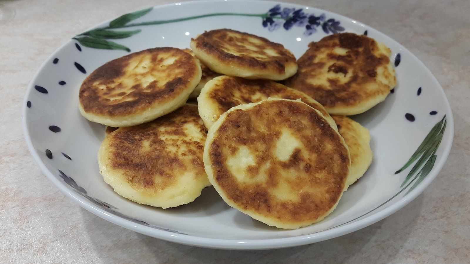 Румяные сырники горкой на белой тарелке