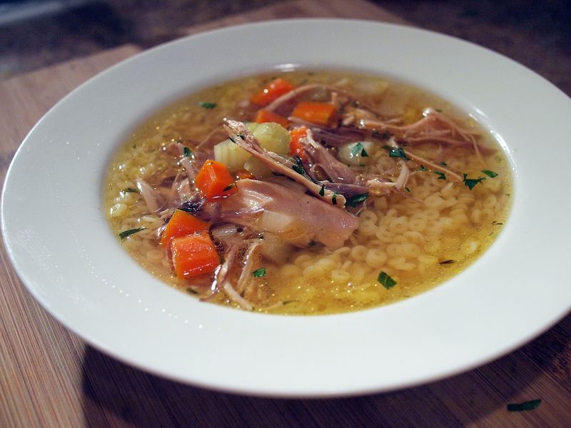 Куриный суп с лапшой, морковью и зеленью в тарелке