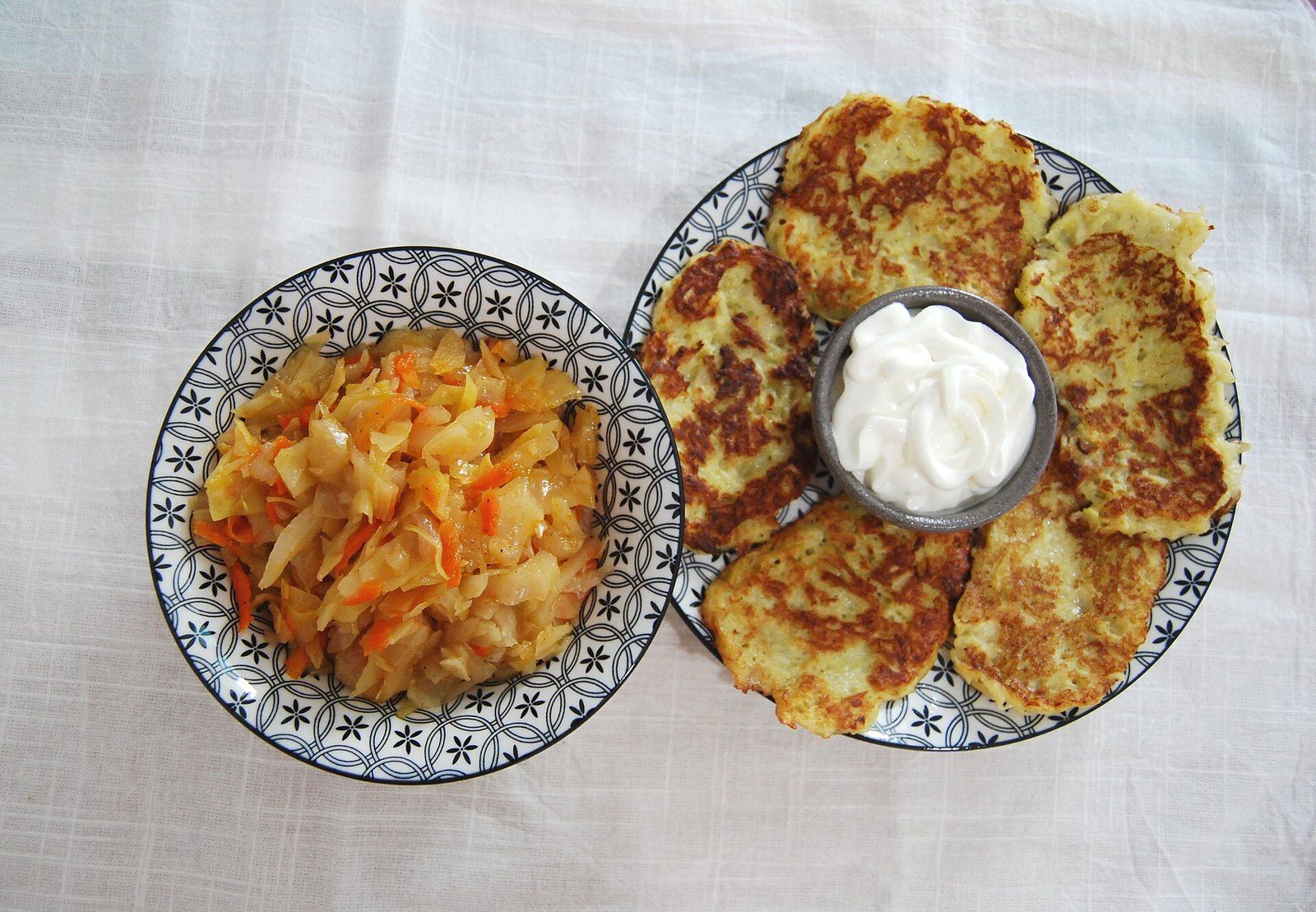 Тушёная капуста с морковью в миске, рядом драники со сметаной