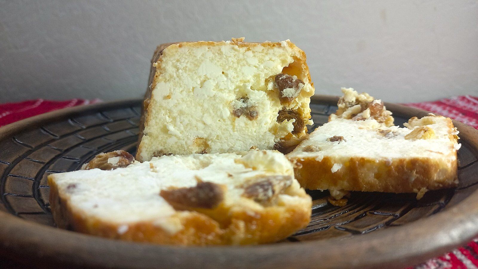 Ломти творожной запеканки с изюмом и румяной корочкой на глиняной тарелке