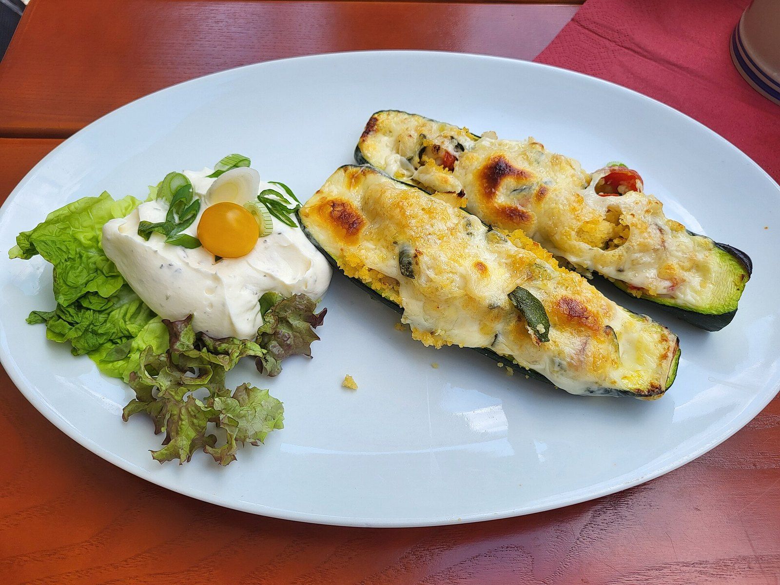 Половинки кабачков, запечённые с сыром, с салатом и соусом